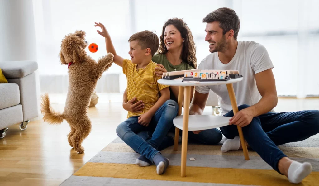 Familie spielt mit Hund in der Wohnung